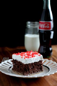 a piece of cake sitting on top of a plate next to a bottle of coke