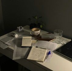 an open notebook sitting on top of a desk next to a laptop computer and cup