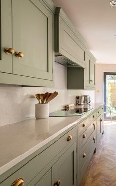 a kitchen with green cabinets and wooden flooring next to a sliding glass door that leads to an outside deck