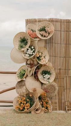 there are many hats stacked on top of each other near the beach and grass fence