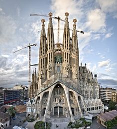 a very large building with many spires on it's sides and construction cranes in the background