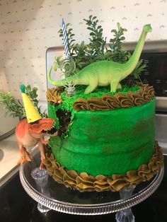 a dinosaur cake with green frosting and decorations