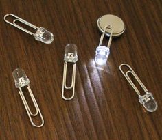 three binders and two paper clips on a wooden table with a metal clip in the middle