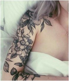 a woman laying in bed with tattoos on her arm