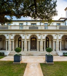 a large white house with two black planters in front of it