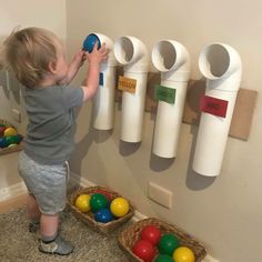 a little boy playing with some balls on the wall