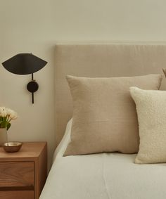 a bed topped with pillows next to a night stand and lamp on top of it