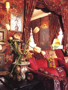 a living room filled with red couches and pictures on the wall next to a window