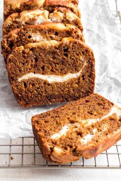 sliced loaf of carrot bread sitting on top of a cooling rack with white frosting