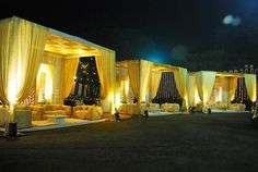 an outdoor event with yellow drapes and couches, lights on the walls and curtains