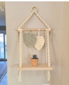 a potted plant sitting on top of a wooden shelf next to a wall hanging