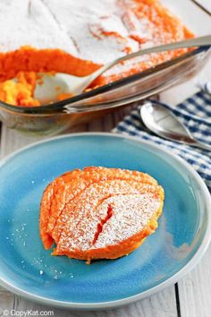 a blue plate topped with powdered sugar next to a casserole dish