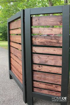 a wooden fence with black slats on the sides and green trees in the background