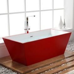 a red bath tub sitting on top of a wooden floor