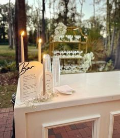 a white table with candles and menus on it in front of a chair outside