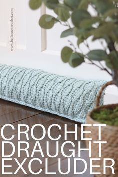 the cover of crochet draught excluder is shown next to a potted plant