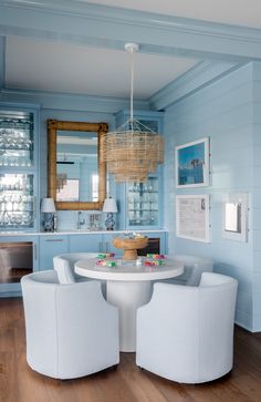 a dining room with blue walls and white chairs around a round table in the center