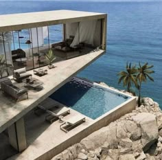 an oceanfront house with a pool and lounge chairs on the cliff overlooking the water