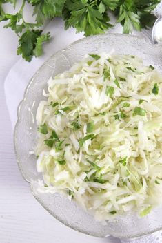 shredded cabbage in a glass bowl with parsley on the side