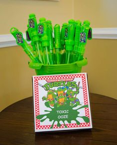 there are many green plastic toothbrushes in the cup on the table with a card