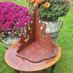 a wooden chair sitting on top of a table next to potted plants and flowers