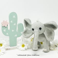 an elephant sitting next to a cactus and some daisies