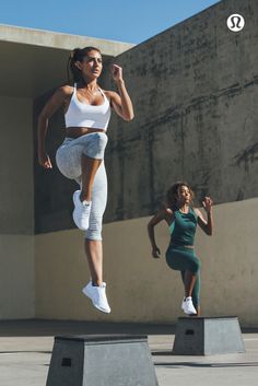 two women are jumping in the air with their feet up and one is wearing white