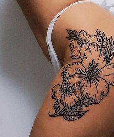 a close up of a woman's thigh with flowers on the side and leaves