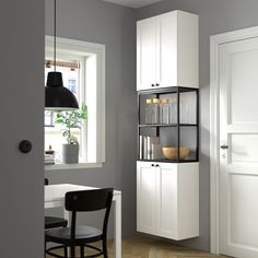 a room with a table, chair and shelves in it next to a door that has a potted plant on the window sill