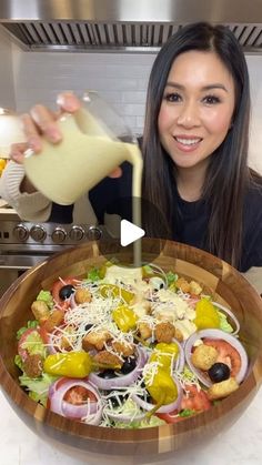 a woman pouring dressing over a salad in a bowl