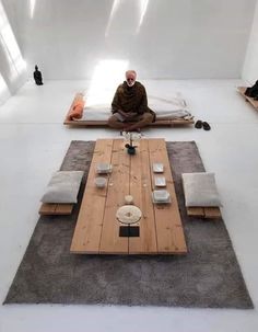 a man is sitting on the floor in front of a coffee table and couches