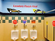 three urinals in a men's bathroom with signs on the wall above them