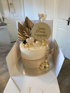 a white cake sitting on top of a table next to a box filled with cookies