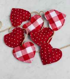 red and white hearts tied to twine on a marble counter top with gold chains