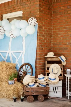 hay bales, hats and balloons are on display in front of a brick wall