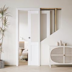 an open door leading to a bedroom with a plant in the foreground and a bed in the background