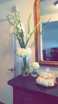 a vase filled with white flowers sitting on top of a table next to a mirror