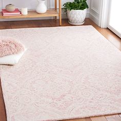 a pink rug on the floor in front of a white shelf and potted plant