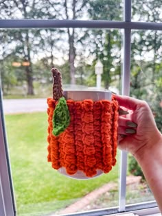 someone holding up a cup holder made out of crocheted yarn with a leaf on it