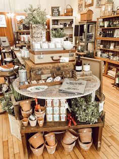 a room filled with lots of potted plants and pots on top of a wooden table