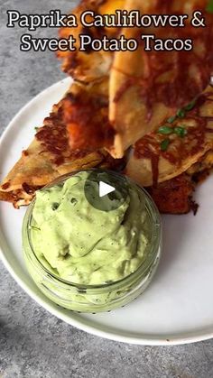 a plate topped with pizza and guacamole next to a bowl of sauce