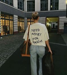 a woman walking down the street with bags and a t - shirt that says need money for frisbee