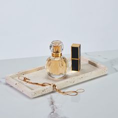 a bottle of perfume sitting on top of a white tray next to a gold and black object