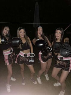 four young women in black and pink outfits posing for the camera with boxing gloves on