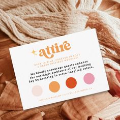 a business card sitting on top of a pile of wood chips with the words attire written in orange and pink