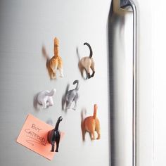 a refrigerator with magnets on the door and several cats stuck to it's side