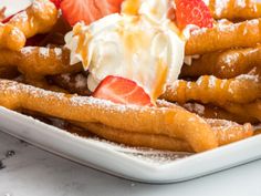 a white plate topped with waffles covered in whipped cream and strawberries