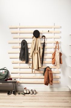 a coat rack with several coats and shoes hanging on it's side, next to a bench