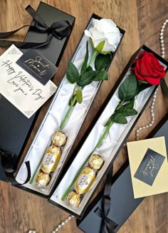 two roses in a box with some chocolates and a red rose on the table