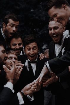 a group of men in tuxedos standing around each other with their hands together